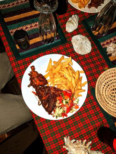a plate of food with meat and french fries on a table at Mawe Mawili in Tanga