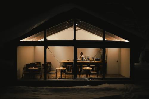 un hombre está sentado en una mesa en una habitación con un mantel en Country Inn Milky House, en Niseko