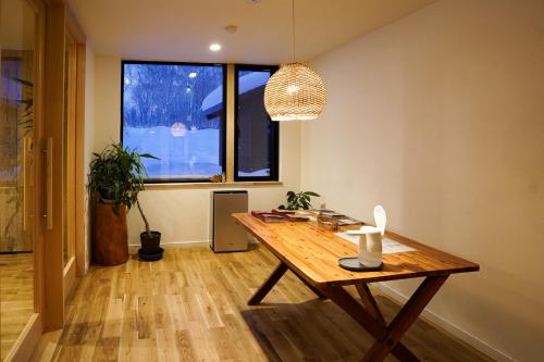 a room with a wooden table and a window at Country Inn Milky House in Niseko