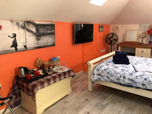 Canterbury HOMESTAY Ensuite في كانتربيري: غرفة نوم بجدران برتقالية وسرير وطاولة