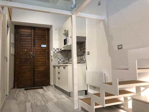 a kitchen with white walls and a wooden door at Trescene Room Locazione Breve Turistica in Benevento