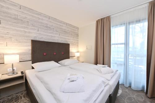 a bedroom with a large white bed and a window at Aquamaris Strandresidenz Rügen in Juliusruh
