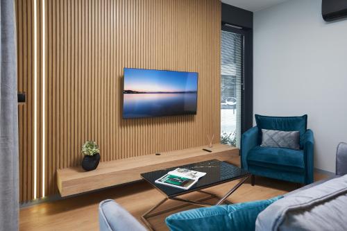 a living room with a blue chair and a television on a wall at Apartamenty Olimpijska by RENT4YOU in Olsztyn