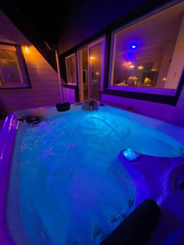 a jacuzzi tub in a room with purple lighting at Le poséidon, gîte EXCEPTIONNEL face à la mer avec spa, terrasse, 4 chambres UN VRAI COUP DE COEUR in Fécamp