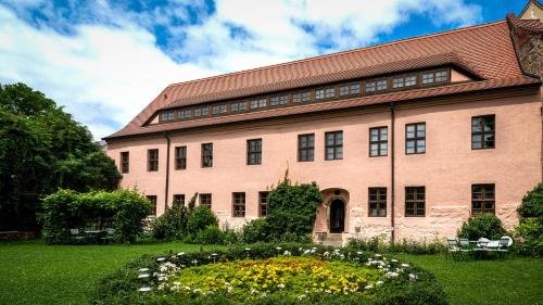 a large brick building with a garden in front of it at Hotel Cranach-Herberge City Centre in Lutherstadt Wittenberg