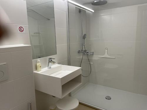 a white bathroom with a shower and a sink at Fewo 2 am Auweg in Hirschegg