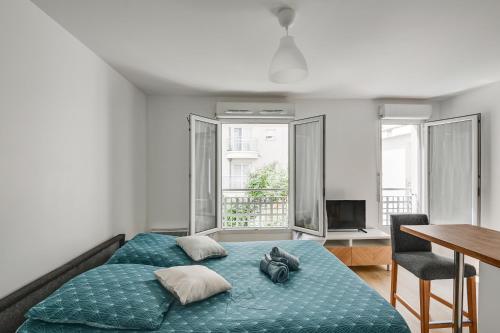 um quarto com uma cama azul, uma secretária e janelas. em La Vallée-Chatenay Malabry em Châtenay-Malabry