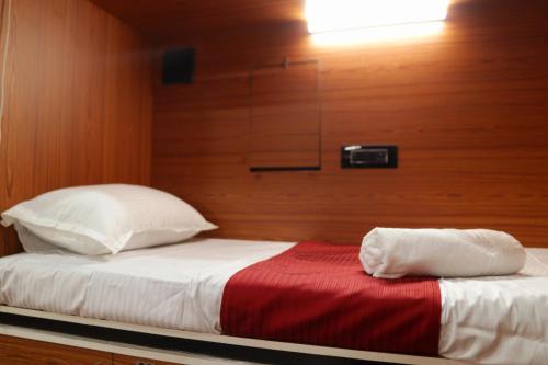 a bed with white pillows and a red blanket at Rahul Men's AC Dormitory in Navi Mumbai