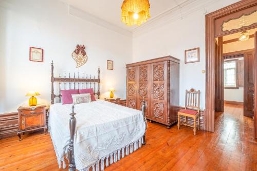 a bedroom with a bed and wooden floors and a chandelier at Casa da Celeira in Ponte de Lima