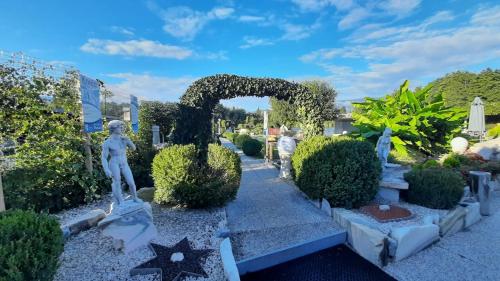 a garden with a arch and statues in a yard at Hotel Seestuben in Villach