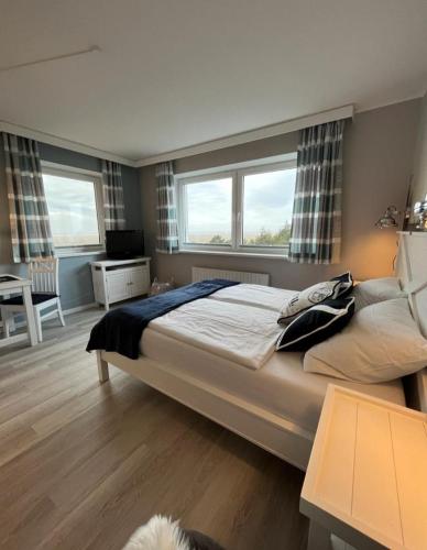 una camera con un grande letto e due finestre di Ferienwohnung Meeresblick Cordy a Sankt Peter-Ording