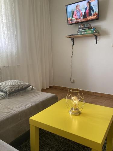 a room with a yellow table and a tv on the wall at Apartmán ANA in Terchová