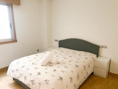 a bedroom with a white bed with a green headboard at Apartamento acogedor con vistas al mar. in A Coruña