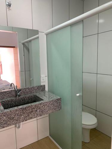 a bathroom with a sink and a toilet and a mirror at HOTEL POUSADA POR DO SOL in Pato Branco