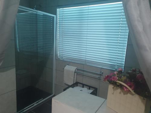 a bathroom with a toilet and a window with blinds at DOTJJ B & B in Paarl