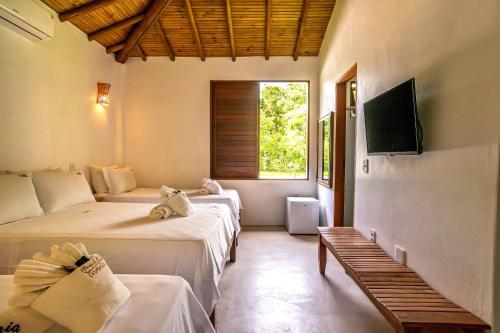 a room with three beds and a tv on the wall at POUSADA CARMELITHA in Trancoso