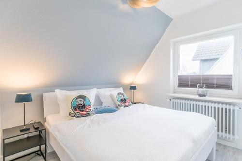 a bedroom with a white bed with two pictures on the pillows at "Haus Deichlodge" deichlodge lodge fünf in Büsum