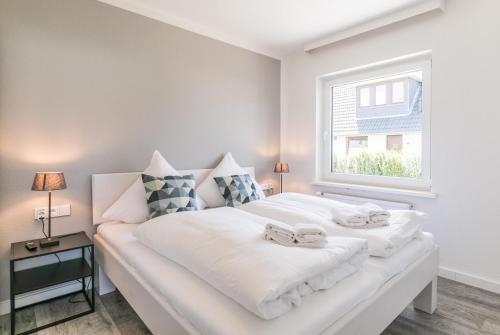 a bedroom with a large white bed with a window at "Haus Deichlodge" deichlodge, lodge eins in Büsum