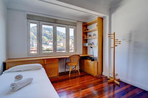 1 dormitorio con cama, escritorio y ventana en Apartamento Ulia by SanSe Holidays en San Sebastián