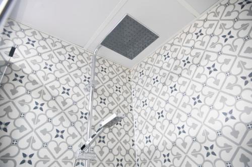 a bathroom with a shower with a tile wall at Hostal Boutique I Host You in Madrid