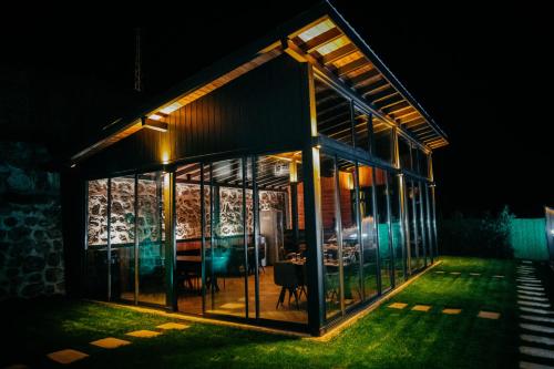 a glass house with a dining room in it at night at Çathan Art Hotel in Ayder Yaylasi