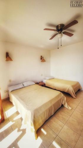 two beds in a room with a ceiling fan at El Gran Velero in Los Órganos