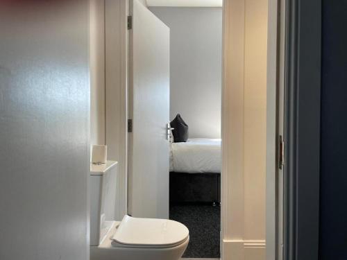 a bathroom with a toilet and a room with a bed at The Lugton Rooms 