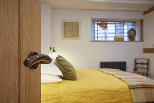 a bedroom with a bed with yellow sheets and a window at Kin Ludlow Rooms in Ludlow