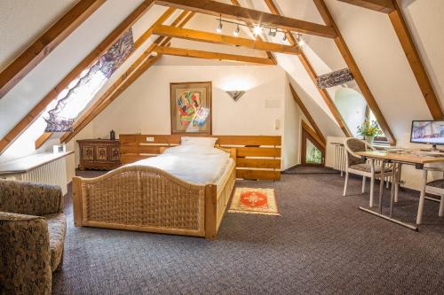 - une chambre mansardée avec un lit et un bureau dans l'établissement Landhaus Amselhof Hinterzarten, à Hinterzarten
