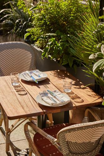 a wooden table with plates and silverware on it at The Hoxton, Downtown LA in Los Angeles