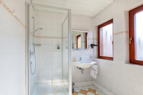 a white bathroom with a shower and a sink at Landgasthof 'Zur Quelle' in Wächtersbach