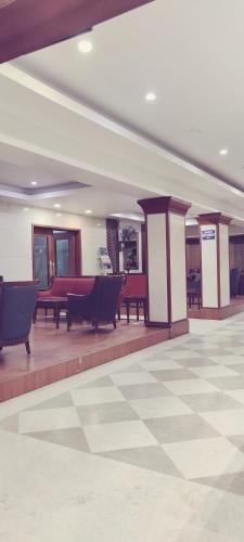 a lobby with benches and tables in a building at Hotel Bhimas Paradise in Tirupati