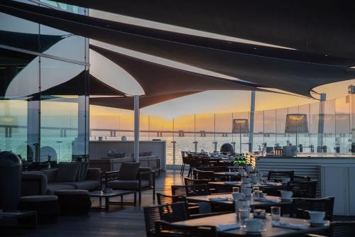 ein Restaurant mit Tischen und Stühlen und Blick auf das Wasser in der Unterkunft MYRIAD by SANA Hotels in Lissabon