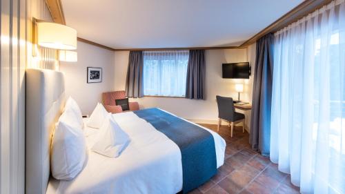 a hotel room with a large bed and a desk at GOLFHOTEL Les Hauts de Gstaad & SPA in Gstaad