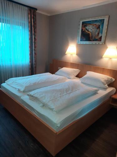 a bedroom with a large bed with white sheets and pillows at Hotel-Gasthof Talblick in Esselbach