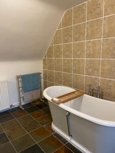 a bathroom with a tub and a tile wall at Harbourside Apartment in Eyemouth