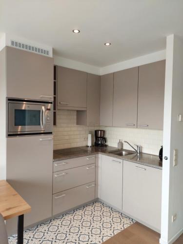 a kitchen with white cabinets and stainless steel appliances at Studio 3 Bredene met strandcabine in Bredene