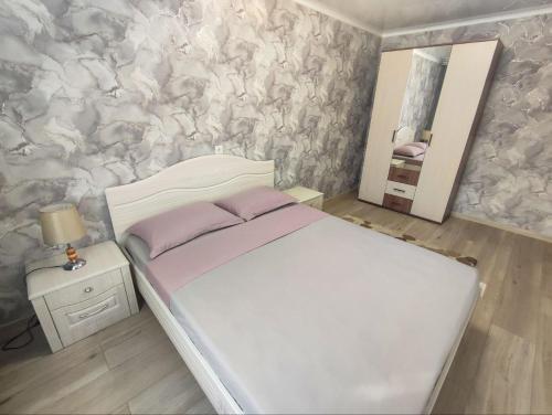 Dormitorio pequeño con cama y espejo en 2-х комнатная квартира в центре на ул.Бородина 107 en Kostanái