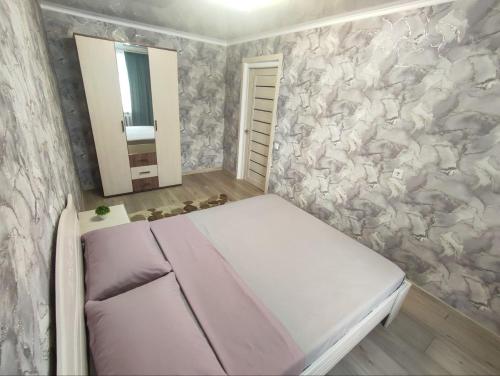 - une petite chambre avec un lit et un miroir dans l'établissement 2-х комнатная квартира в центре на ул.Бородина 107, à Kostanay