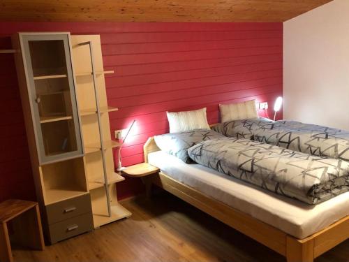 um quarto com uma cama com uma parede vermelha em Haus Konzett em Klösterle