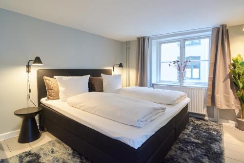 a bedroom with a large bed with white sheets and a window at Perfect Apartment for Friends & Families in central Copenhagen in Copenhagen