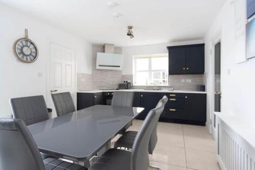 a kitchen with a table and chairs and a clock at Modern newly refurbished house 10 minute walk from Lahinch in Lahinch