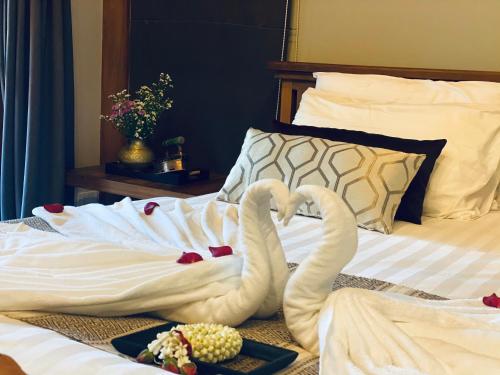 two towel swans sitting on top of a bed at SAK-KA-YA (สัก-กา-ยะ) in Mae Sot