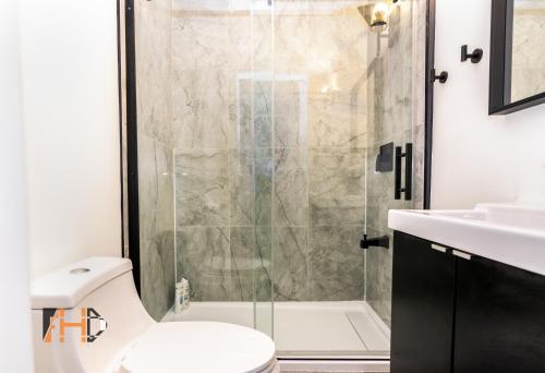 a bathroom with a shower and a toilet and a sink at Downtown Retreat, Spacious 3-Bedroom Urban Getaway in Toronto