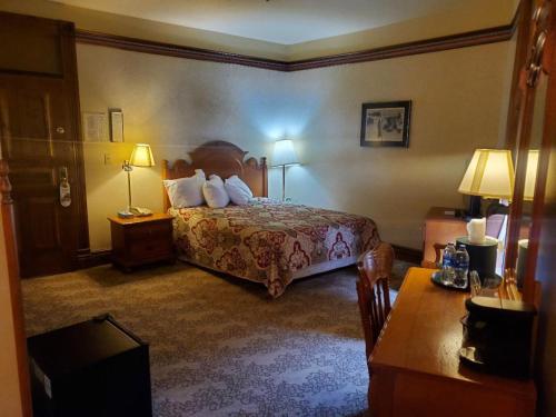 a hotel room with a bed and two tables and two lamps at Historic Bullock Hotel in Deadwood