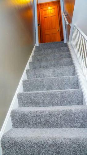 a stairway with a wooden door and a staircase with grey carpet at Spacious 4BR Family & Work-Friendly Home, Close to Airport in Columbus
