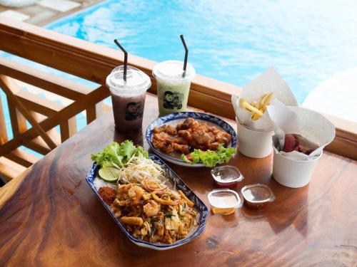 a table with two plates of food and two drinks at ห้างหุ้นส่วนจำกัด บ้านเถ้าแก่ in Ban Muang Baeng