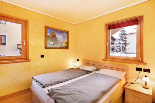 2 Betten in einem Schlafzimmer mit 2 Fenstern in der Unterkunft Red Casa Maurizio in Livigno