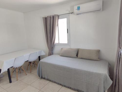 1 dormitorio con cama, escritorio y ventana en Mali Departamento en Mendoza