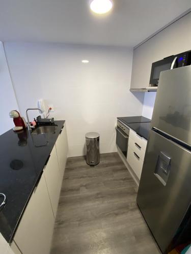 a kitchen with black counter tops and a refrigerator at EUGE Apart in Montevideo